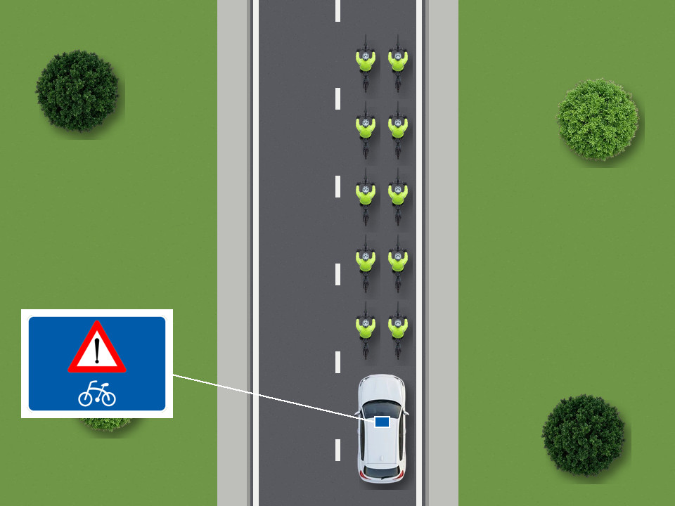A group of cyclists may ride two abreast. The escort car behind them carries the blue roof board.
